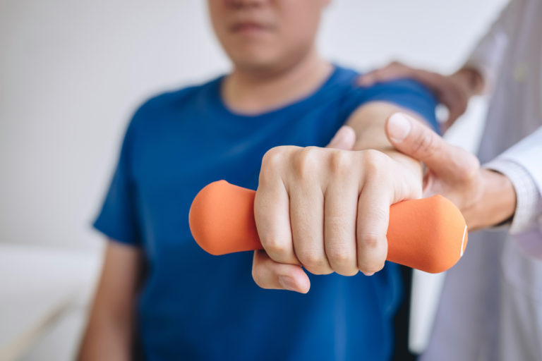 man lifting weight in physical therapy - Adeo physical therapy