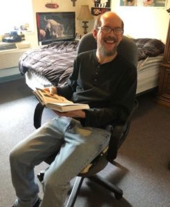 man reading book in his room at Stephens Farm Adeo Brain Injury Services